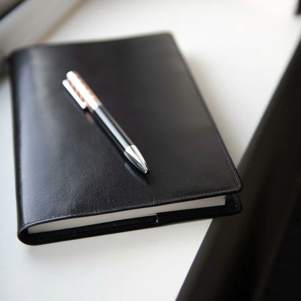 Notebook - A5 Leather Covered, Refillable, in Black - closed shown with pen